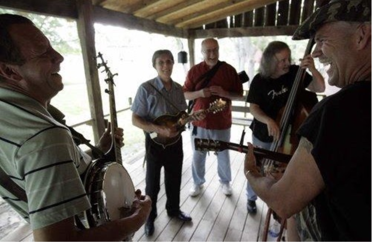 Bluegrass jam session on a porch with banjo, mandolin and upright bass